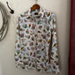 Floral patterned shirt hanging on a hook against a neutral wall.