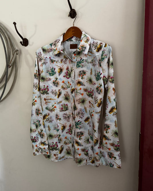 Floral patterned shirt hanging on a hook against a neutral wall.