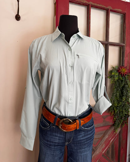 Person wearing a light green shirt and blue jeans with a brown belt, standing in front of a red door.