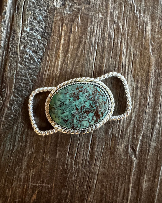 Twilly slide with a large turquoise stone on a wooden surface