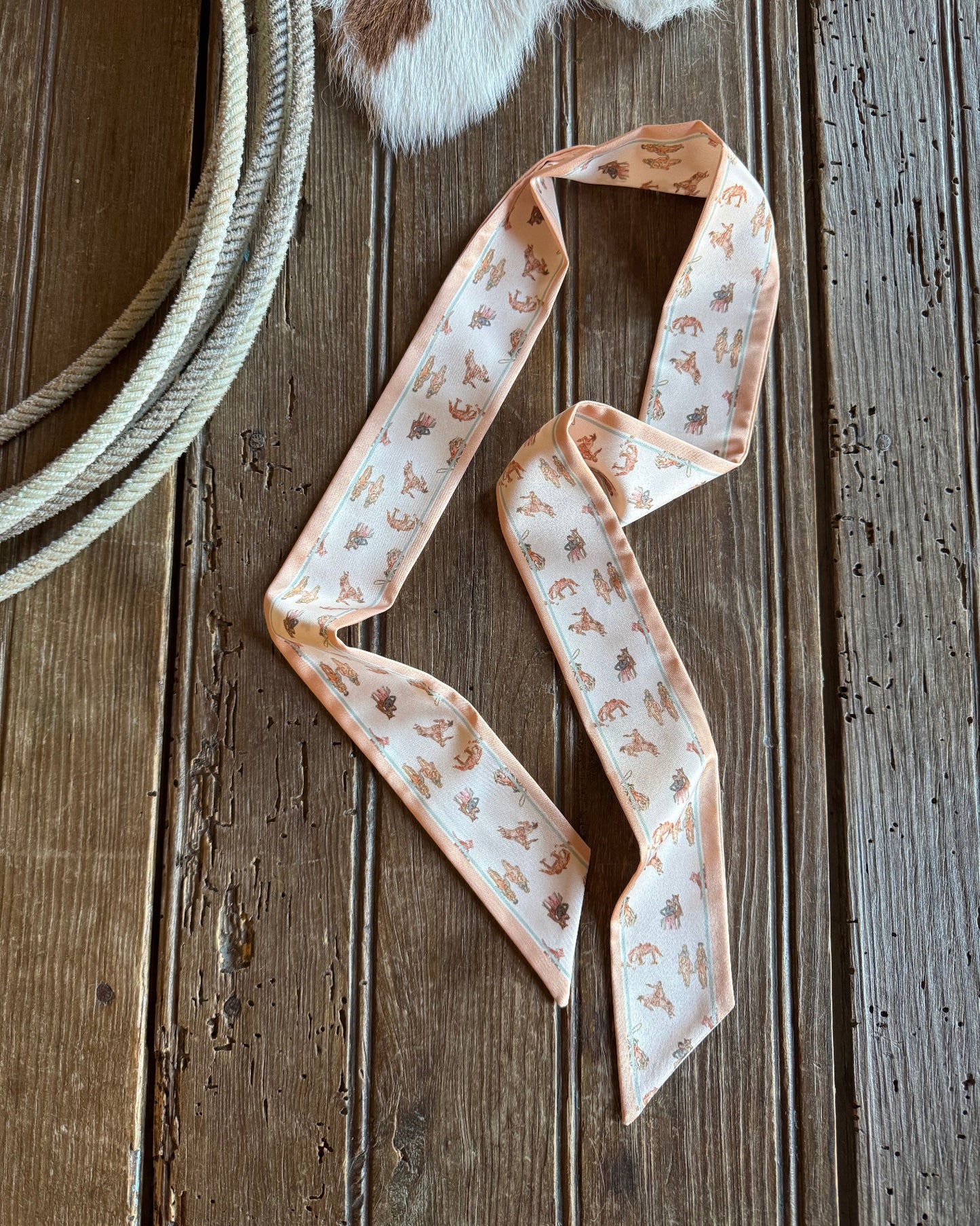 Ribbon scarf on rustic wooden background with rope featuring cowboys