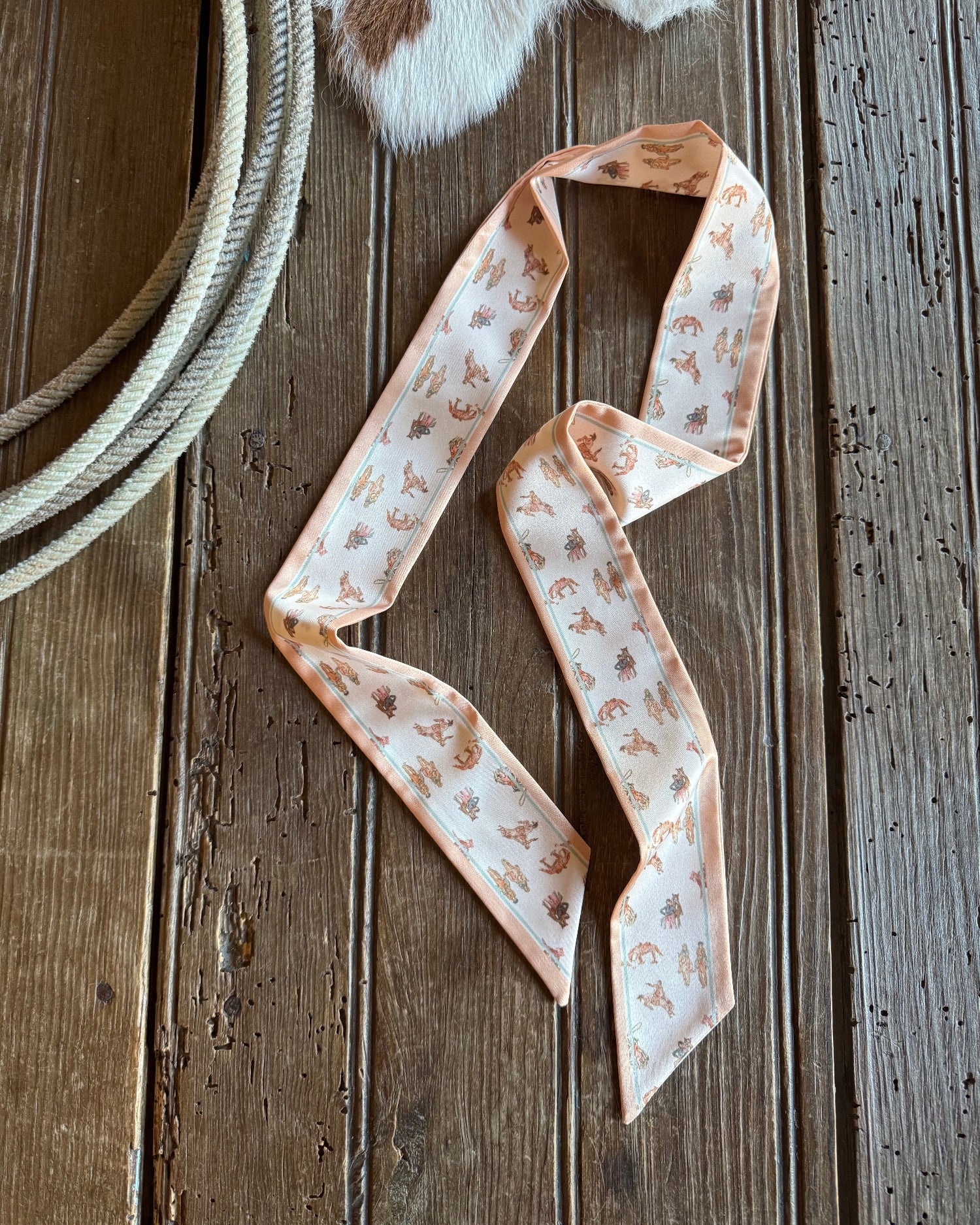 Ribbon scarf on rustic wooden background with rope featuring cowboys