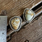 Pair of earrings on a wooden surface with a ruler for scale.