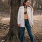 Model standing in trees, dressed in a stylish modern western outfit.