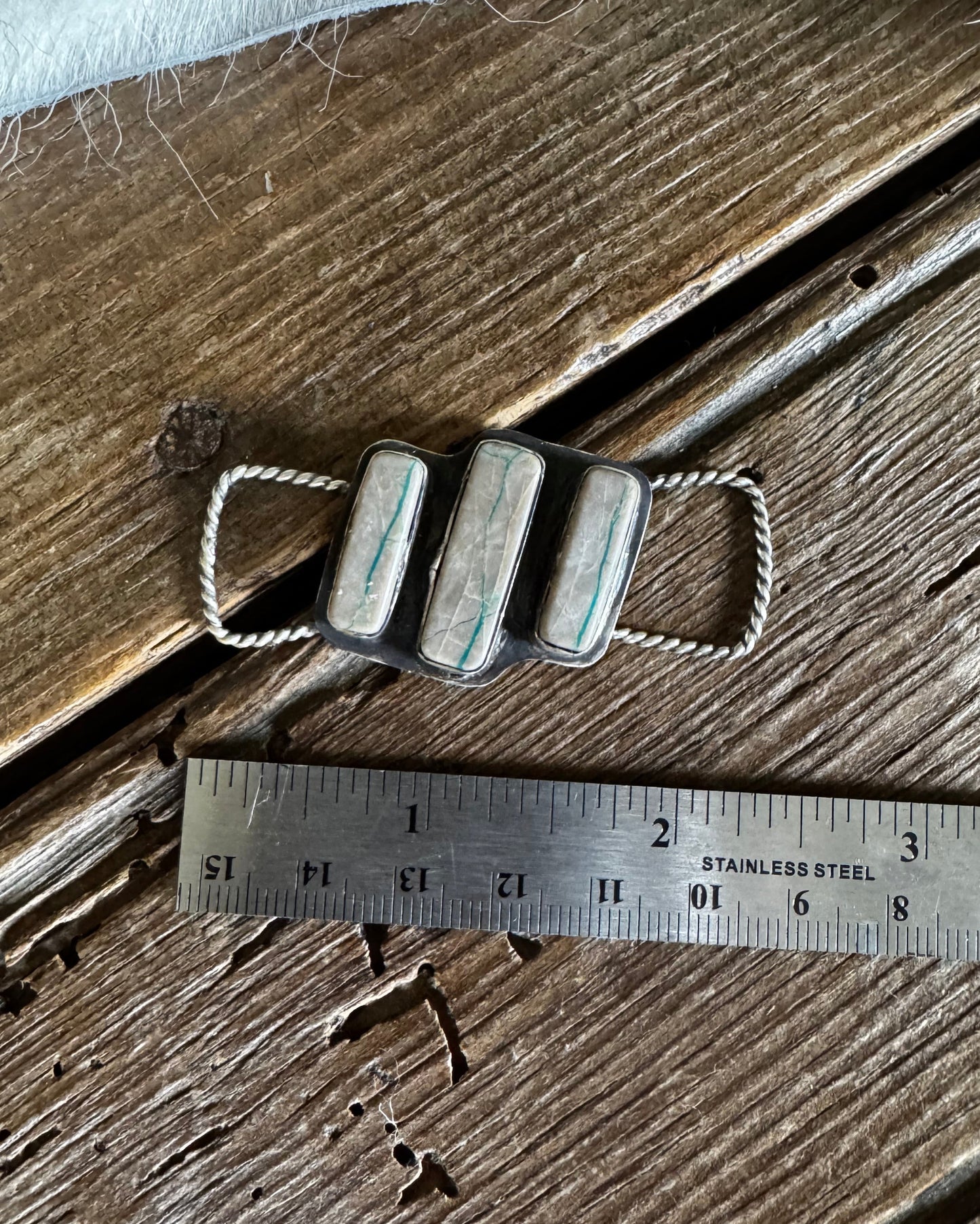 Twilly slide with grey and turquoise stones on a wooden surface with a ruler for scale