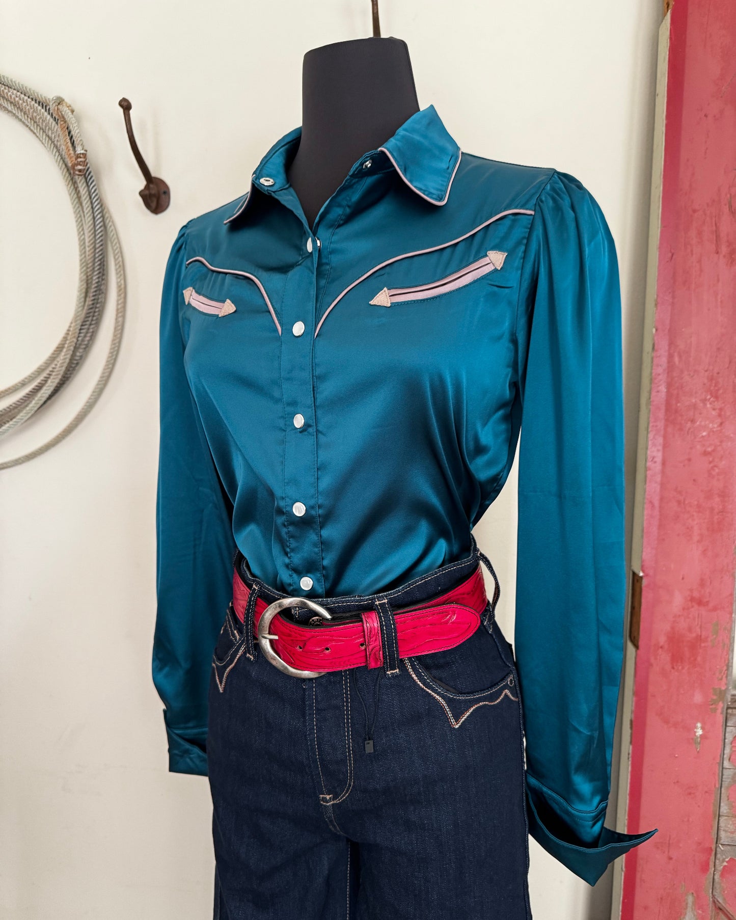 Blue satin shirt on a mannequin with a red belt and jeans with a white background