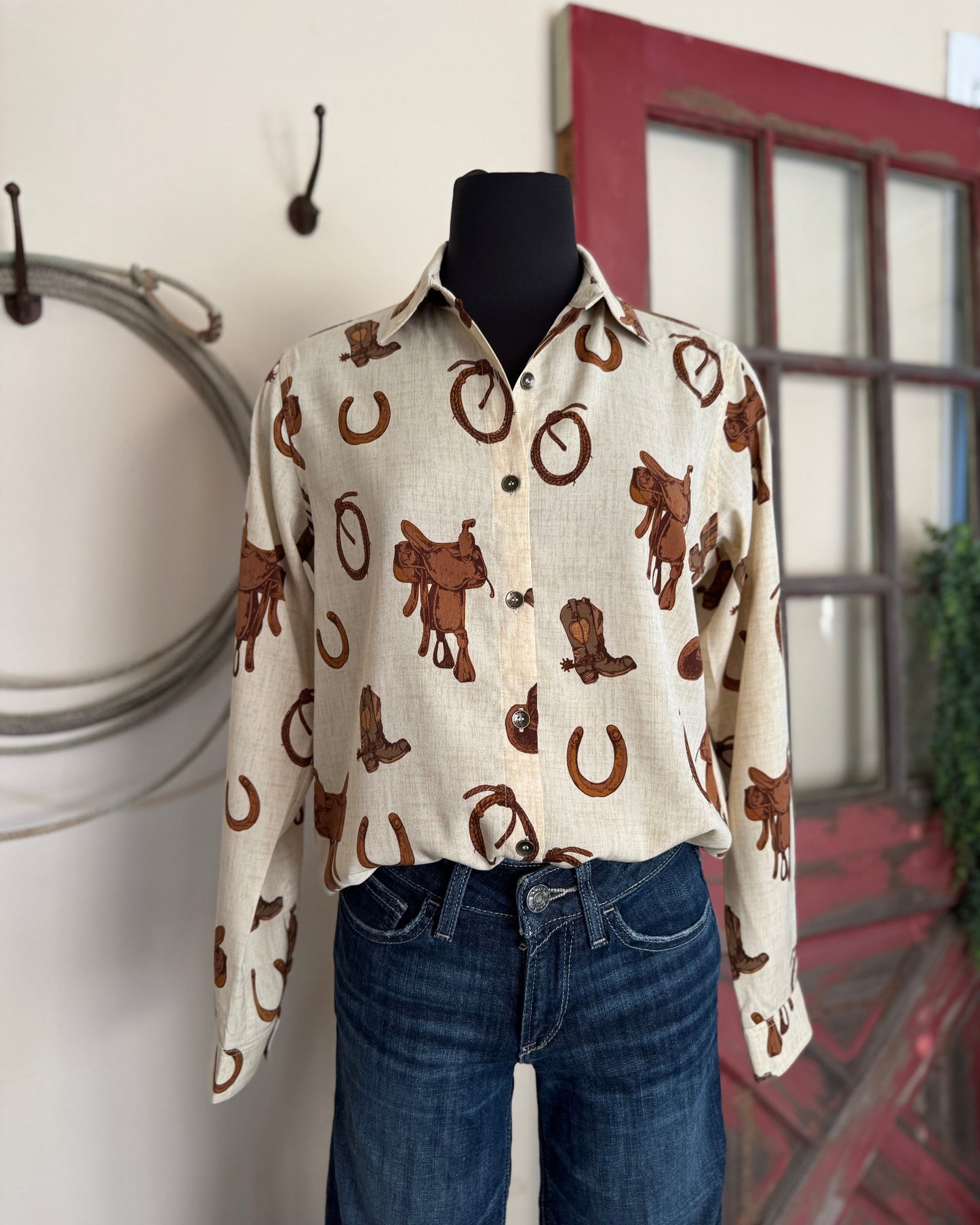 Mannequin wearing a white shirt with brown cowboy pattern and blue jeans against a neutral background.