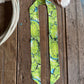 Green patterned cactus scarf on a wooden surface with cowhide leather and white rope.