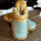 turquoise embossed leather slippers on a rustic wooden table with cowhide background