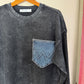 Dark gray corduroy shirt with a patch on a hanger against a beige background