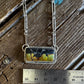 Necklace with a pendant on a wooden surface, measured by a ruler.
