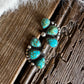 Turquoise earrings on a wooden surface with white fur