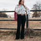 Model standing by a pipe fence in a field, dressed in a stylish modern western outfit.