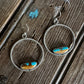 Pair of hoop earrings with turquoise stones on a wooden surface