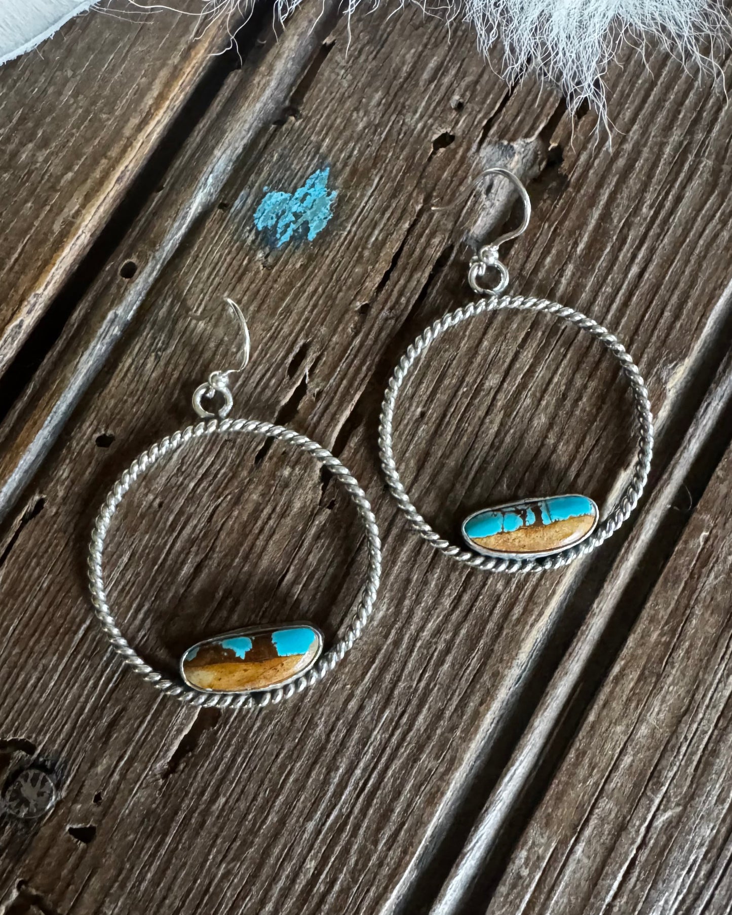 Pair of hoop earrings with turquoise stones on a wooden surface