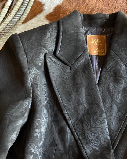 Close-up of a black paisley-patterned jacket with a brand tag on a horse.
