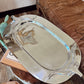Silver tray on a wooden surface with a brown leather chair in the background