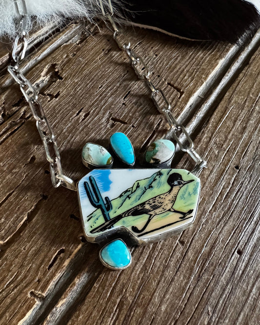 Necklace with a pendant featuring a landscape design on a wooden surface
