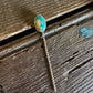 Gold ring with a green stone on a wooden surface