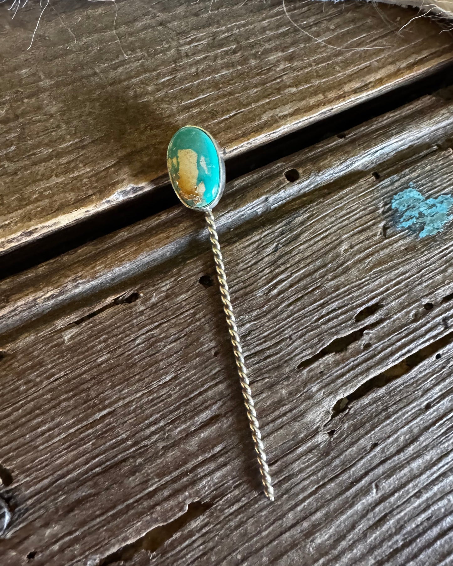 Gold ring with a green stone on a wooden surface