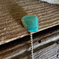 Turquoise stone brooch on a wooden surface