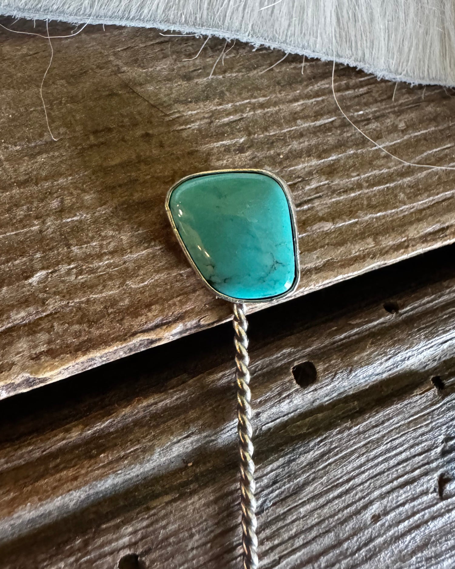 Turquoise stone brooch on a wooden surface