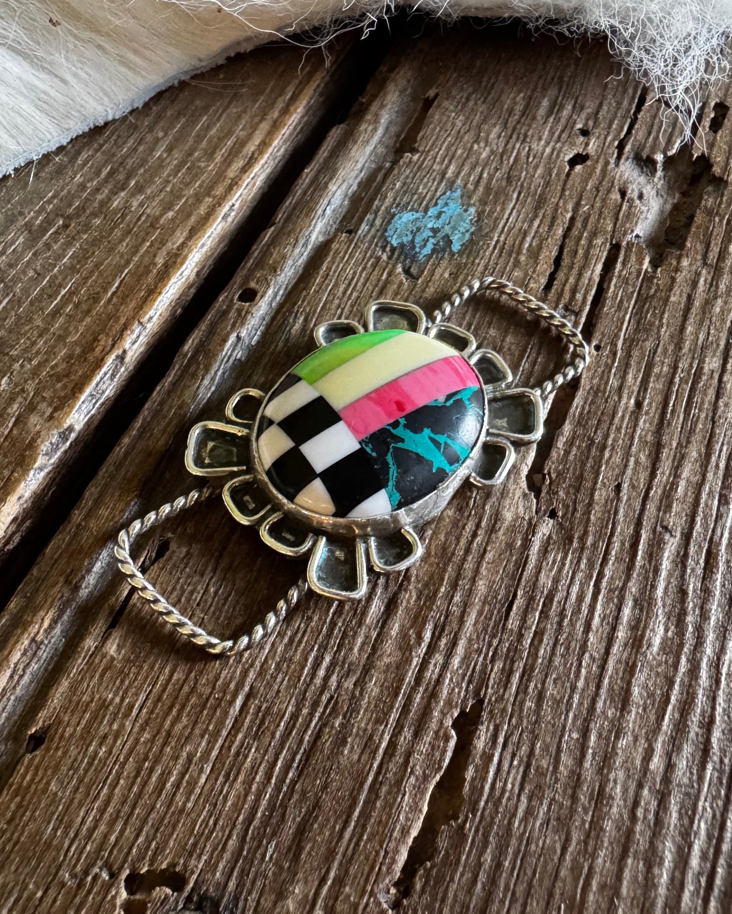 Twilly slide with a colorful pendant on a wooden surface