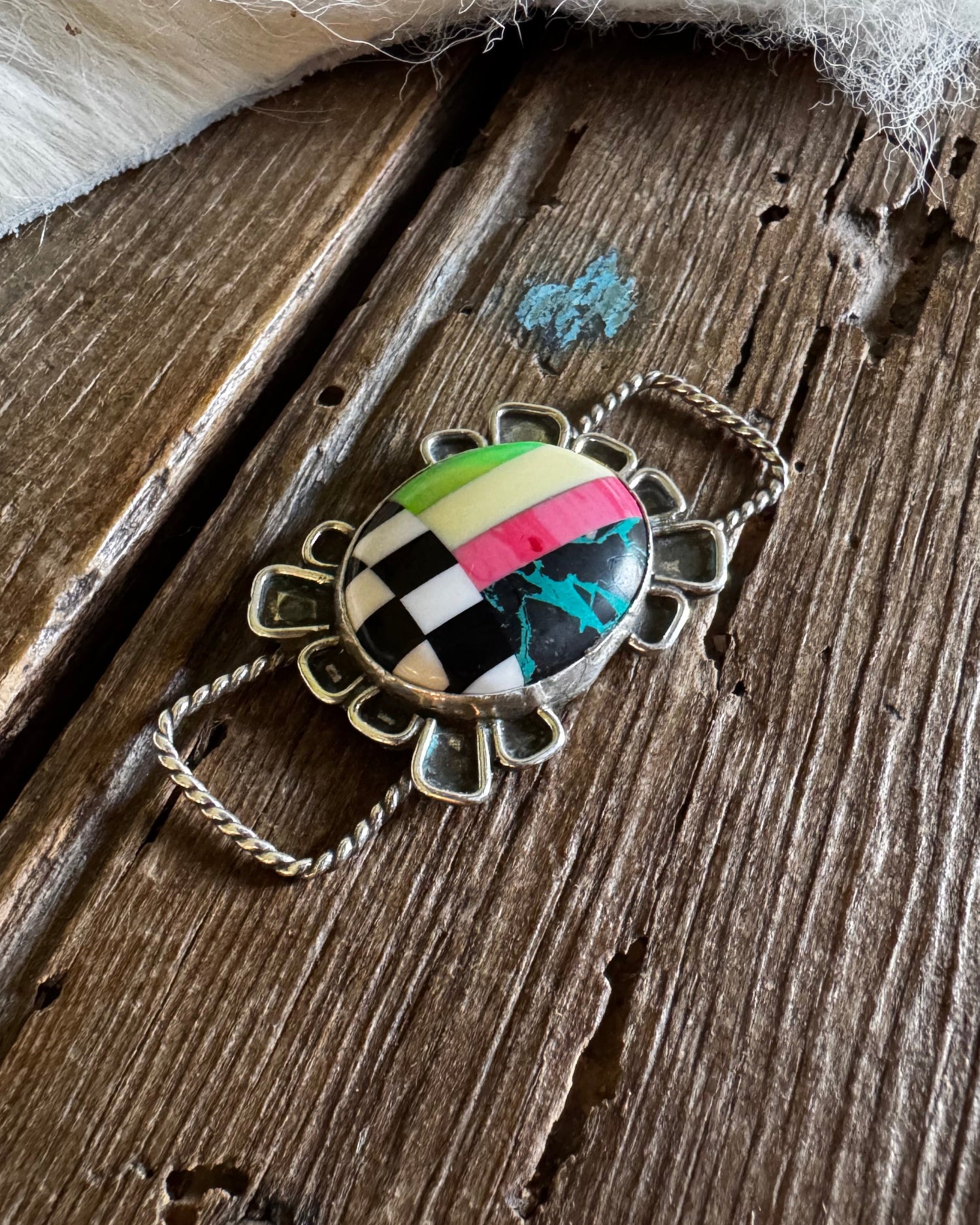 Twilly slide with a colorful pendant on a wooden surface