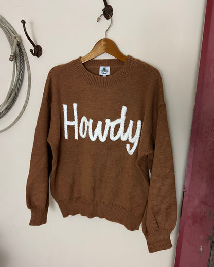 Brown sweater with 'Howdy' text on a white surface
