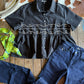 Black embroidered blouse and blue jeans on a wooden surface with cowhide rug in the background