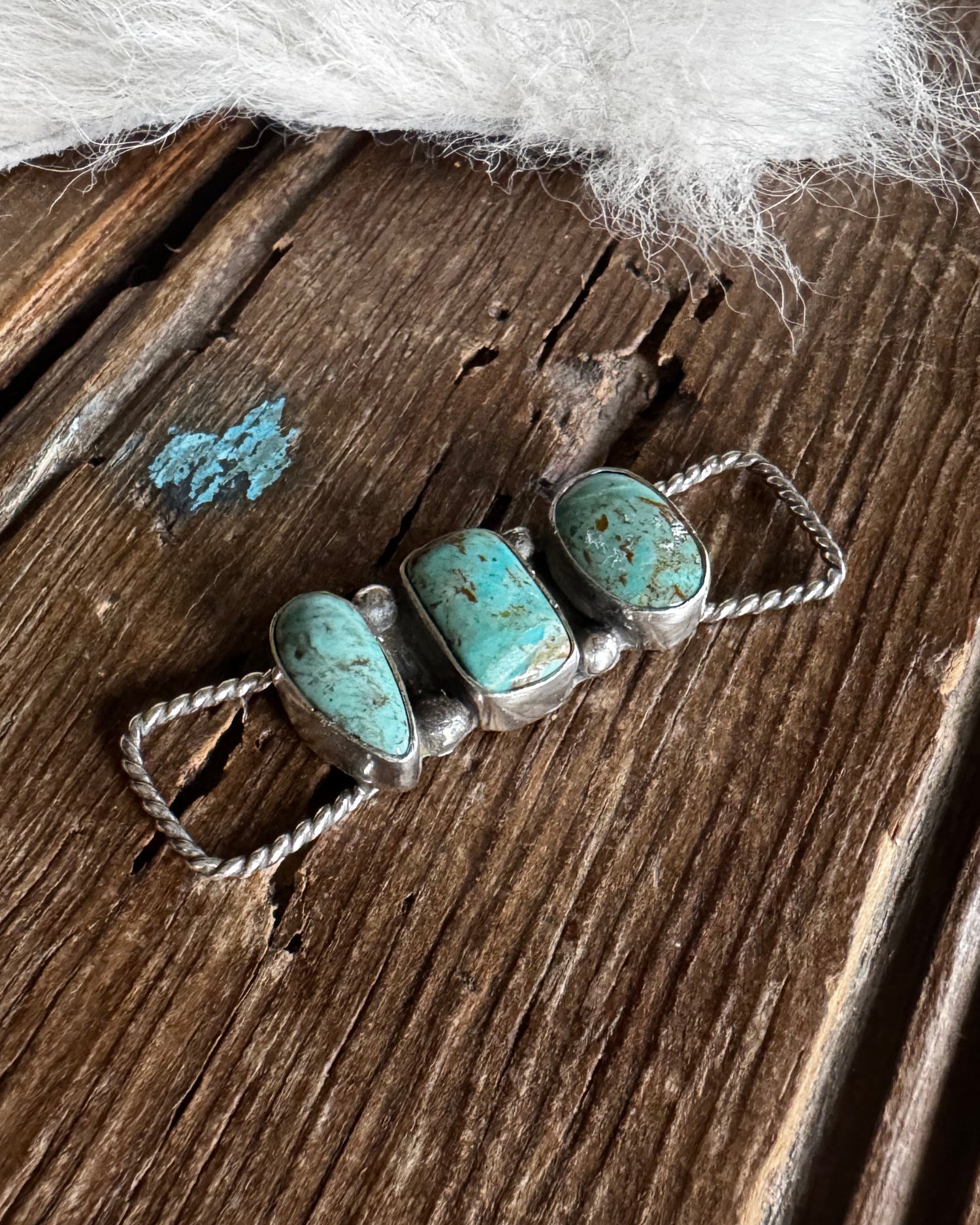 Turquoise stone necklace on a wooden surface with white fur