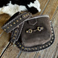 Brown leather bag with studs on a wooden surface