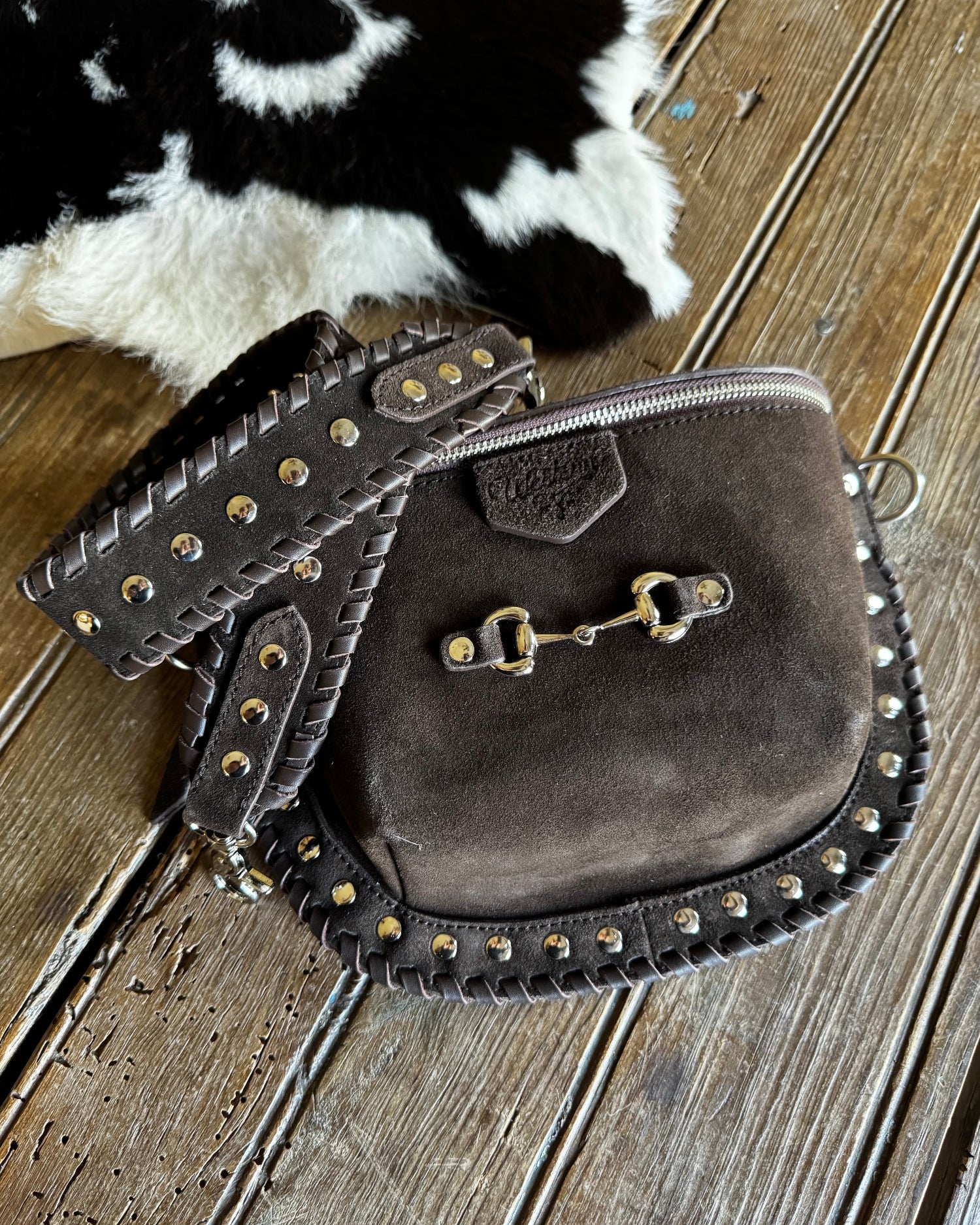 Brown leather bag with studs on a wooden surface