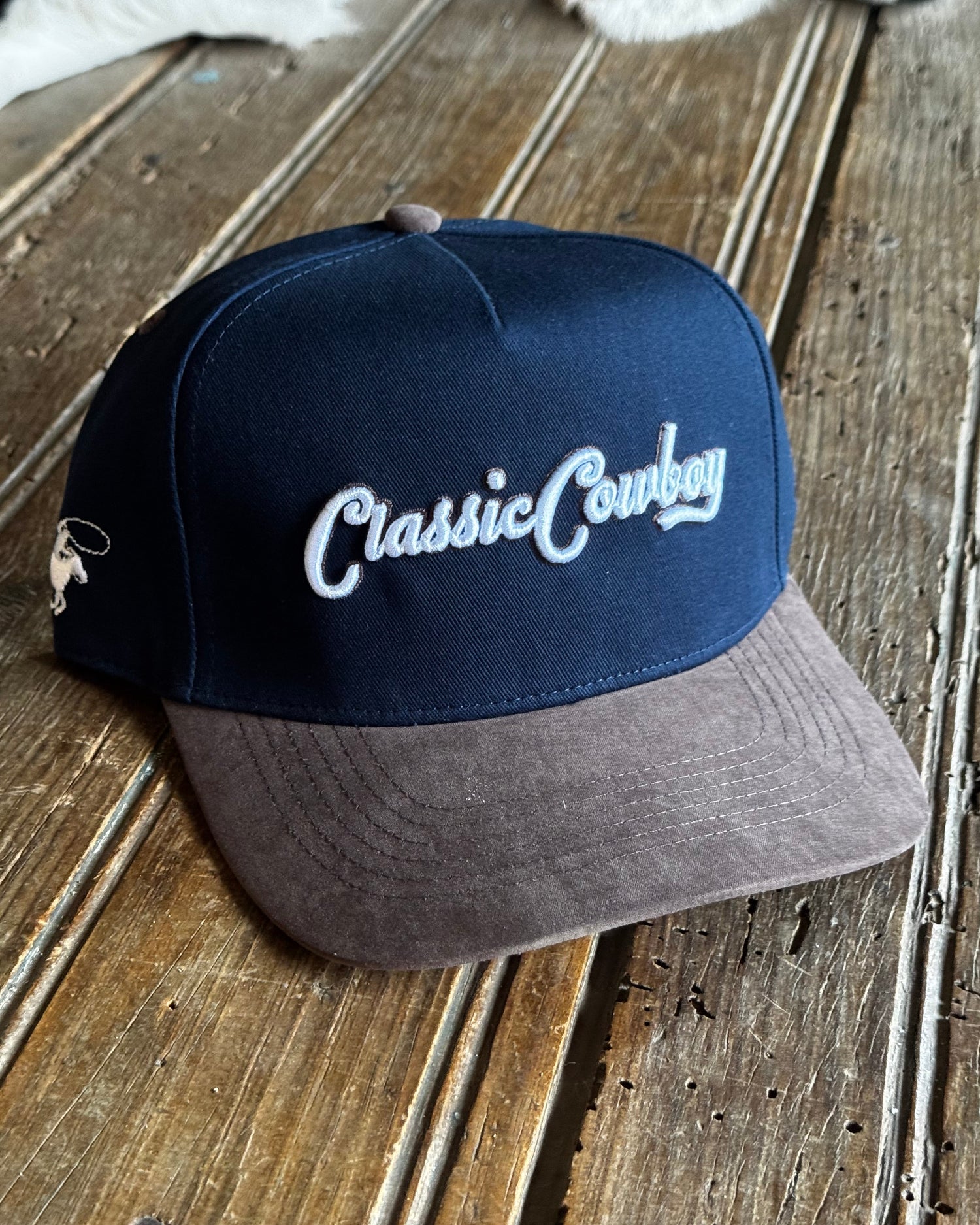 Blue and gray cap with 'Classic Cowboy' text on a wooden surface