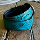Turquoise leather belt with intricate designs on a wooden surface