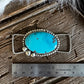 Turquoise pendant with silver frame and pearls on a wooden surface with a ruler for scale.