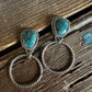 Pair of silver rings with turquoise stones on a wooden surface