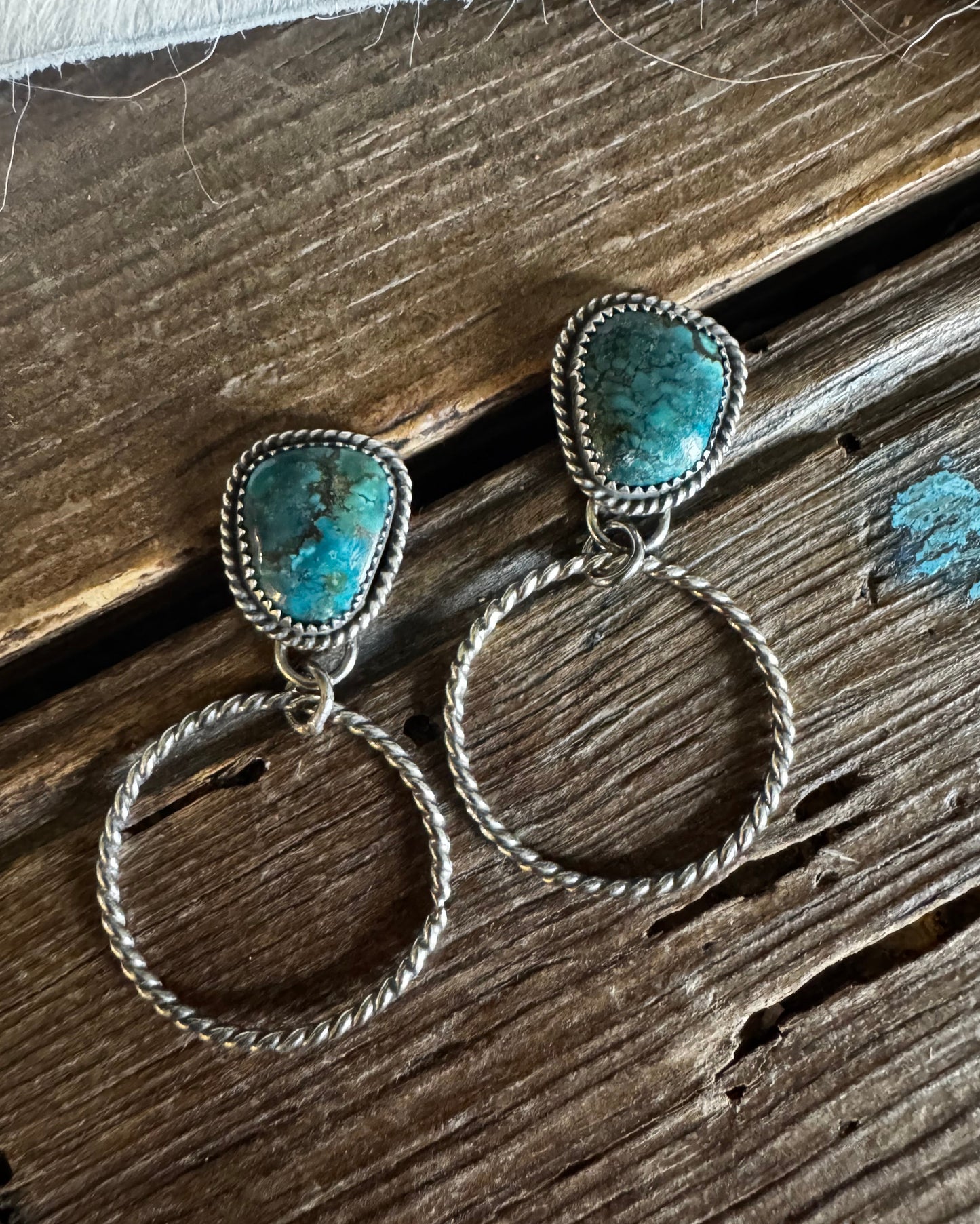 Pair of silver rings with turquoise stones on a wooden surface