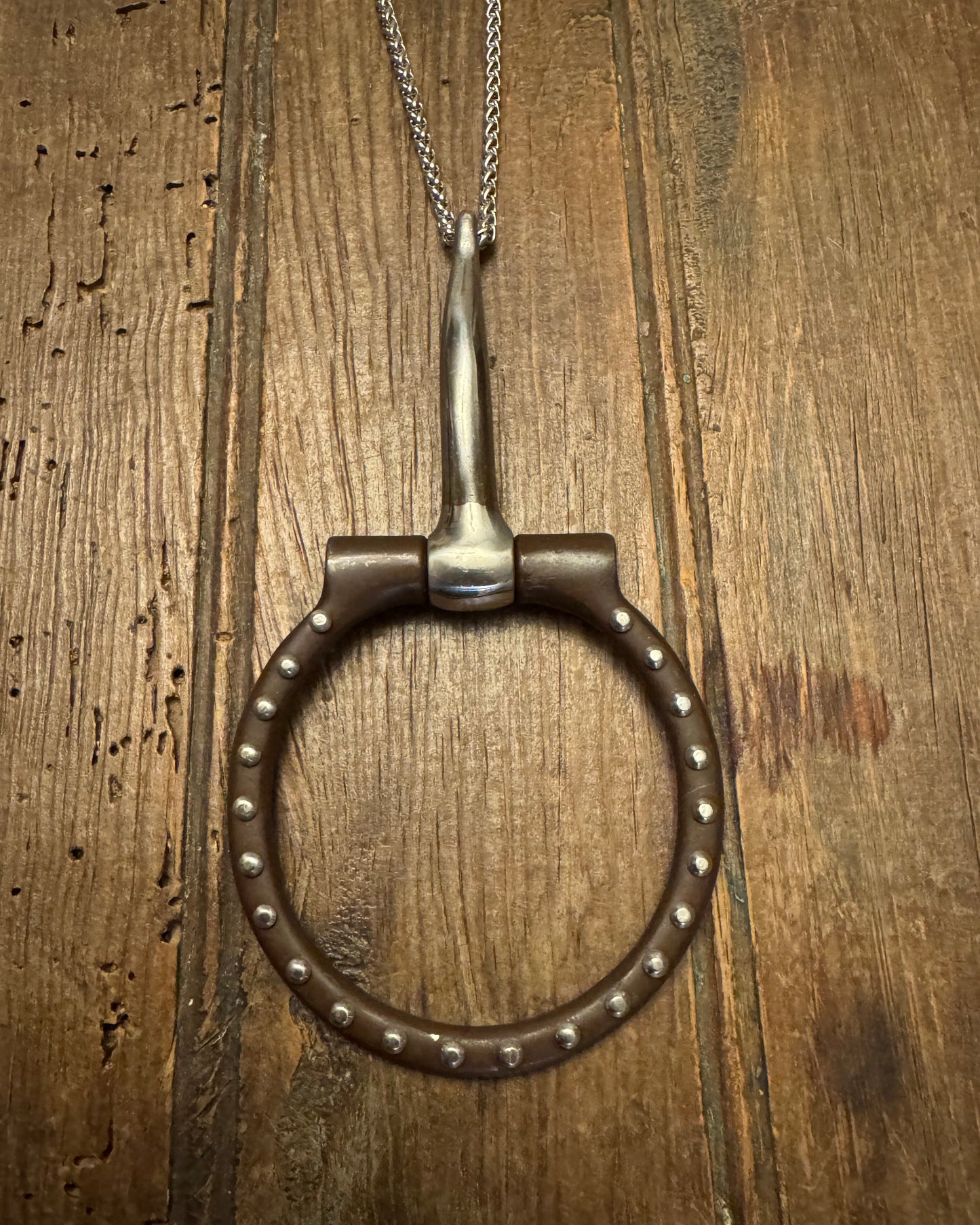 snaffle bit with chain on a wooden surface
