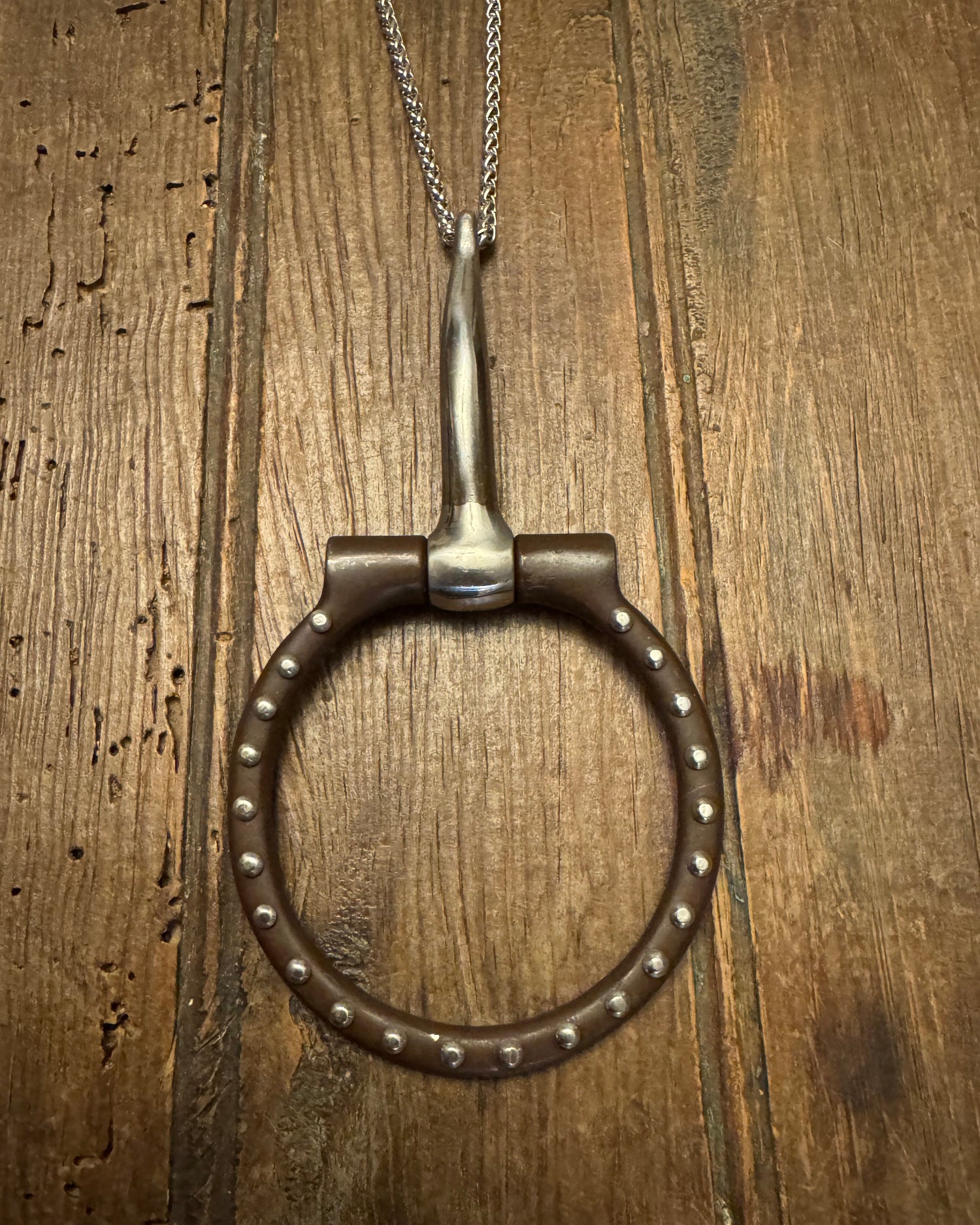 snaffle bit with chain on a wooden surface