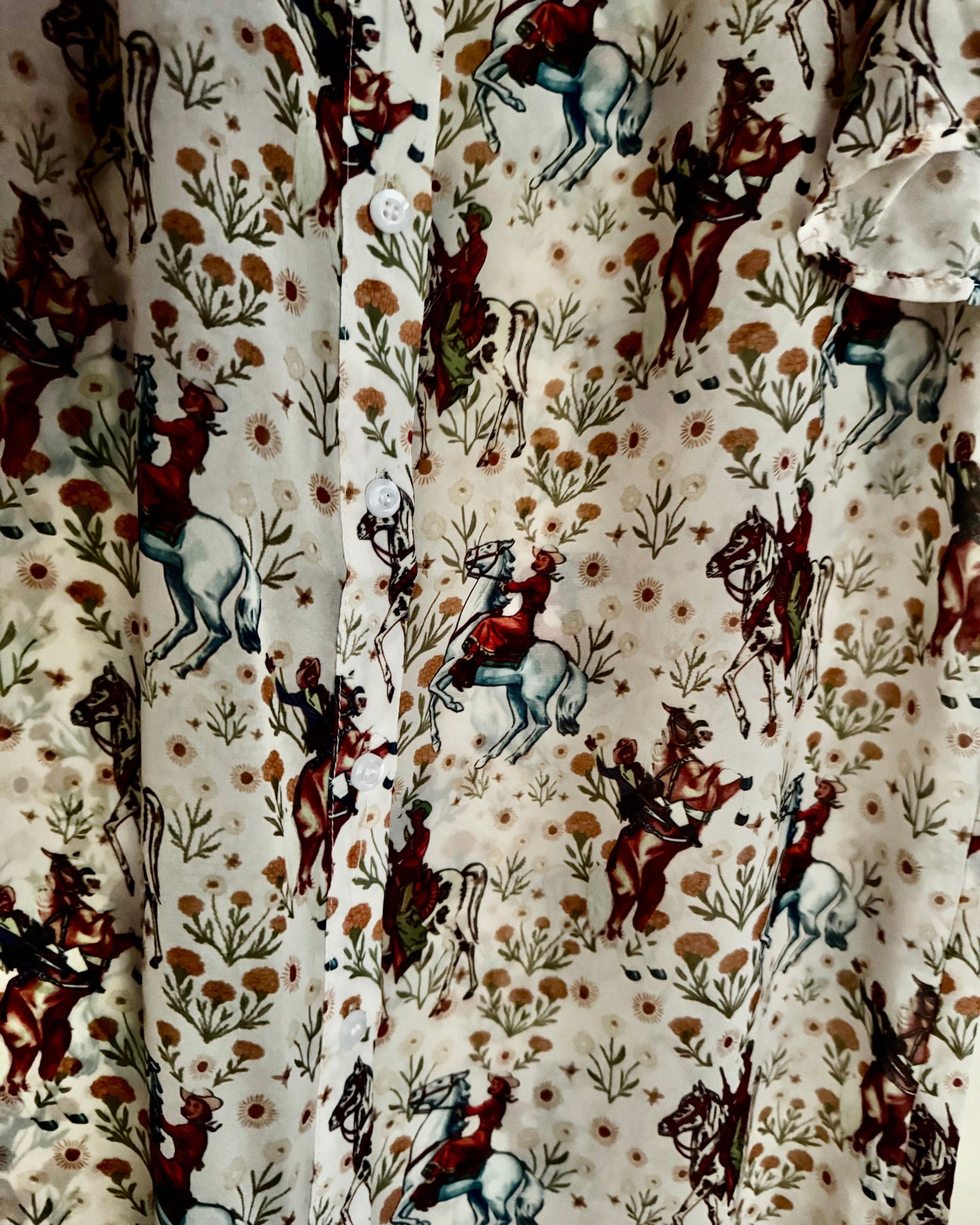 Close-up of a shirt with a pattern of horses and riders on a white background