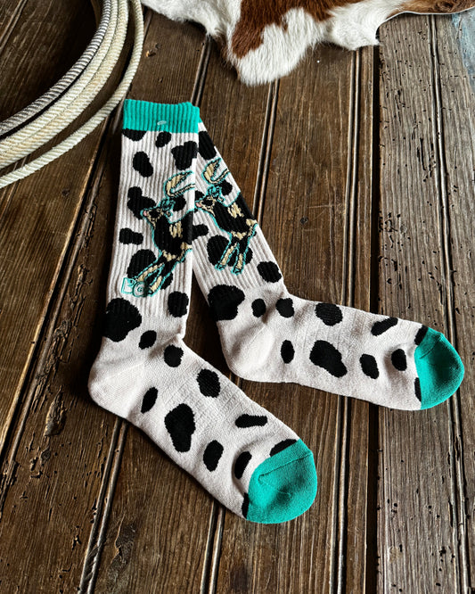 Pair of polka dot socks with teal accents on a wooden surface.