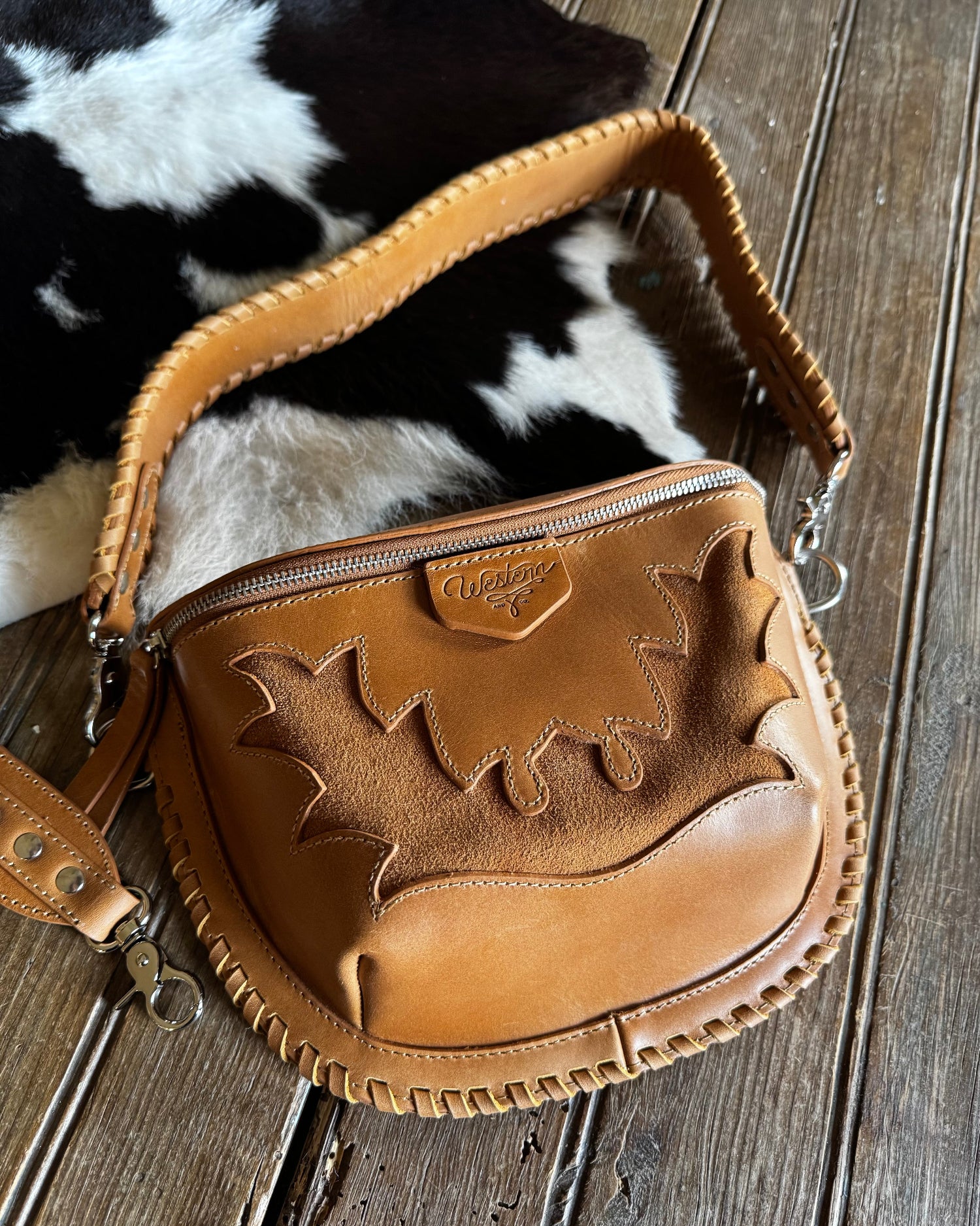 Brown leather bag with decorative patterns on a wooden surface