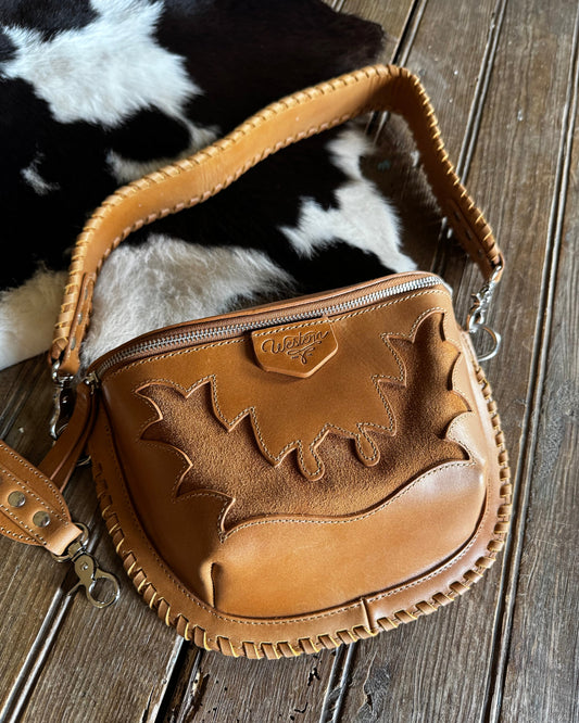 Brown leather bag with decorative patterns on a wooden surface