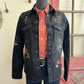 Black denim shirt with embroidered designs on a mannequin against a neutral wall.