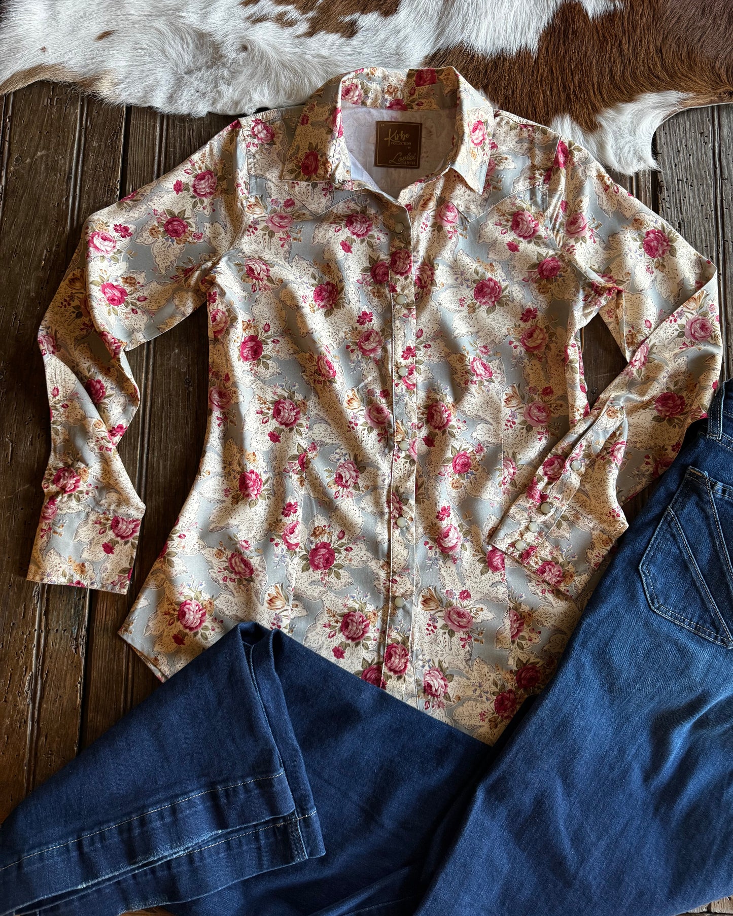 Floral shirt and blue jeans on a wooden surface with cowhide rug