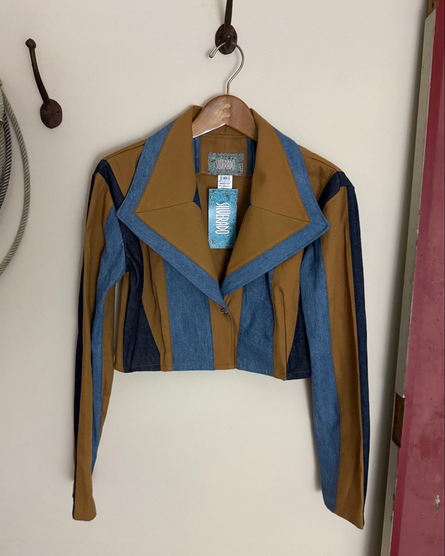 Brown and blue jacket on a white surface with a visible brand tag.