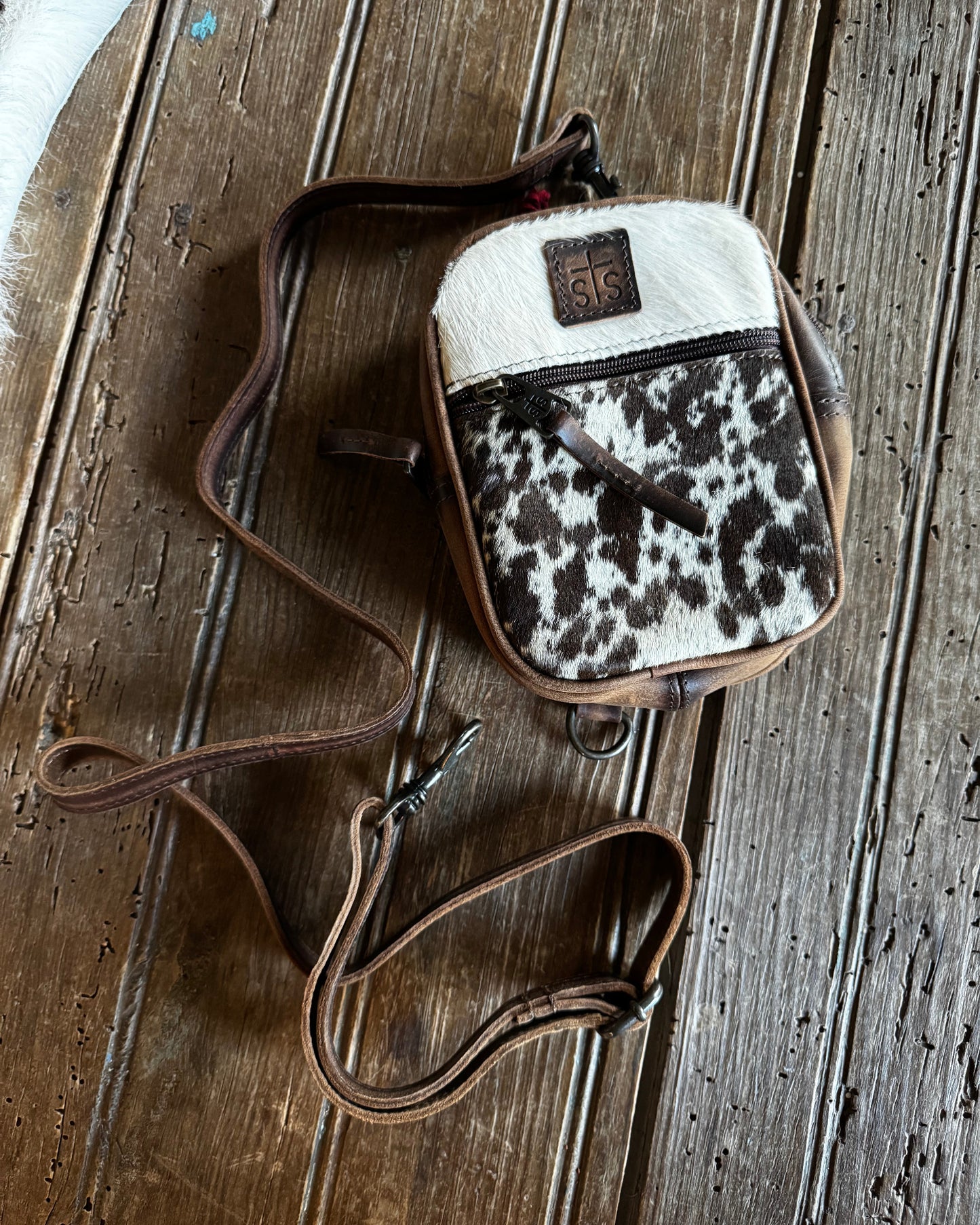 small cowhide crossbody handbag on a wooden surface