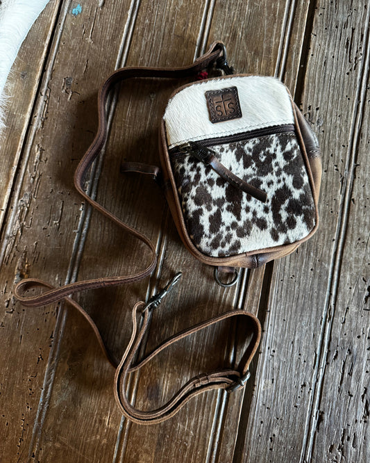 small cowhide crossbody handbag on a wooden surface