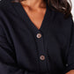 Close-up of a person wearing a black cardigan with buttons.
